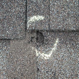 Roof damage from hail on gray roof shingles.