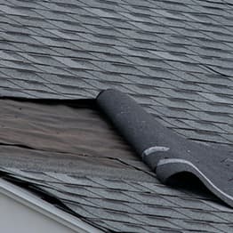 Wind damage to roof on home with gray roofing shingles.