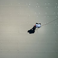 roofer drilling a fastener and plate into a roofing membrane