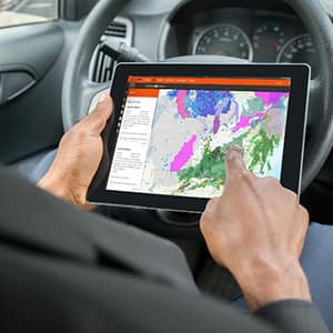 Hombre en un vehículo usando GAF WeatherHub en una tableta.