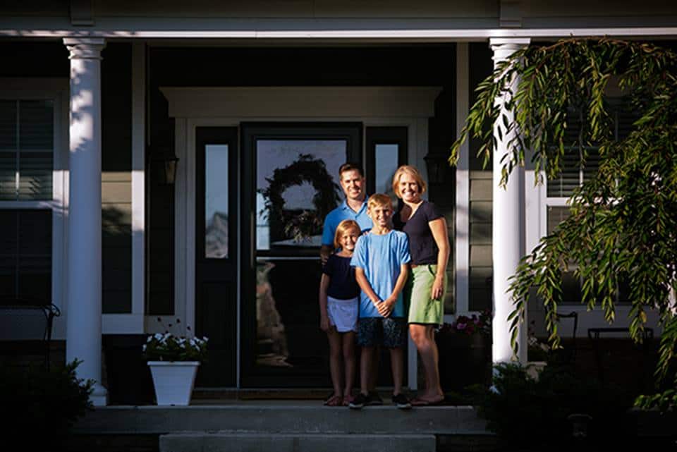 family of four standing outside of their front door