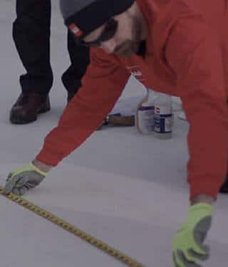 Man in GAF gear measuring a flat roof