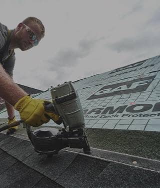 Contractor nailing GAF shingles on a home, one of the six parts of a roof system