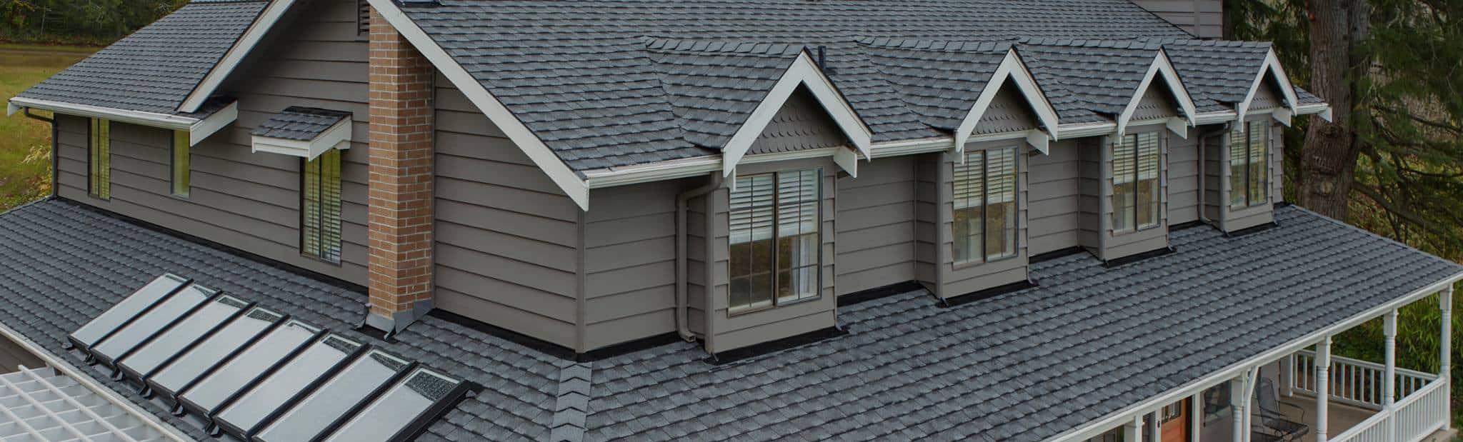 Beige home with close-up of a gray roof featuring new GAF Timberline UHDZ shingles.