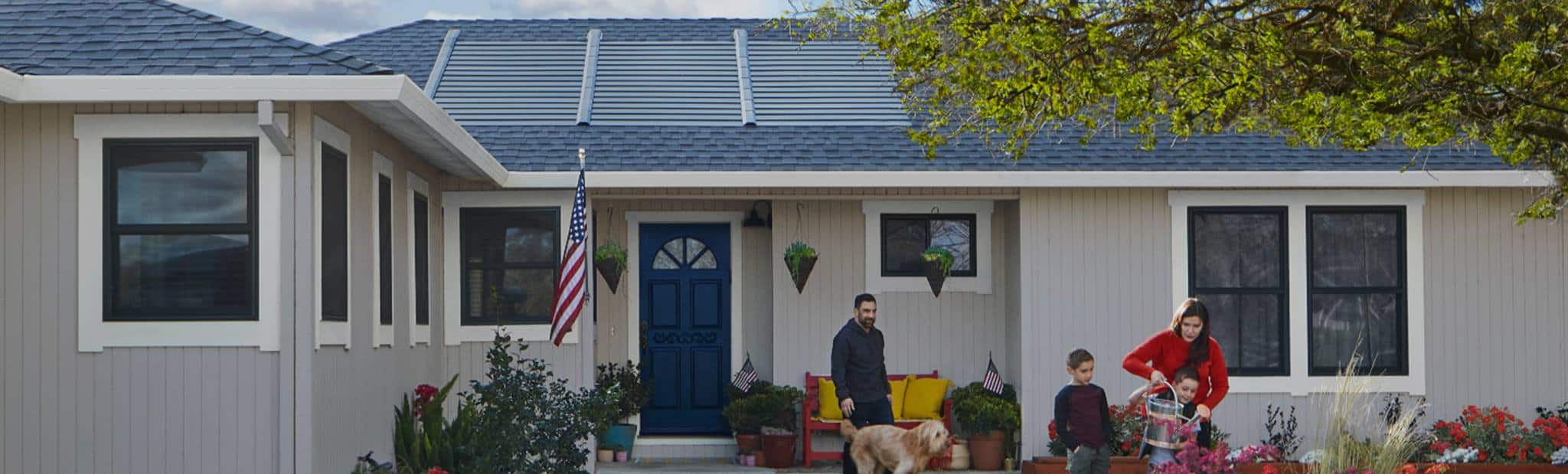 family outside their home featuring solar roof panels