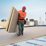 roofer carrying roof boards over roof deck