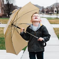 young boy hold an umbrella catching raindrops in his mouth