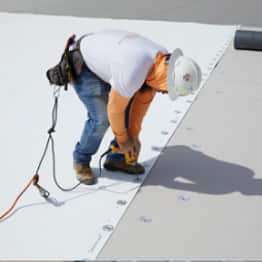 roofer securing fastener and plate to roof