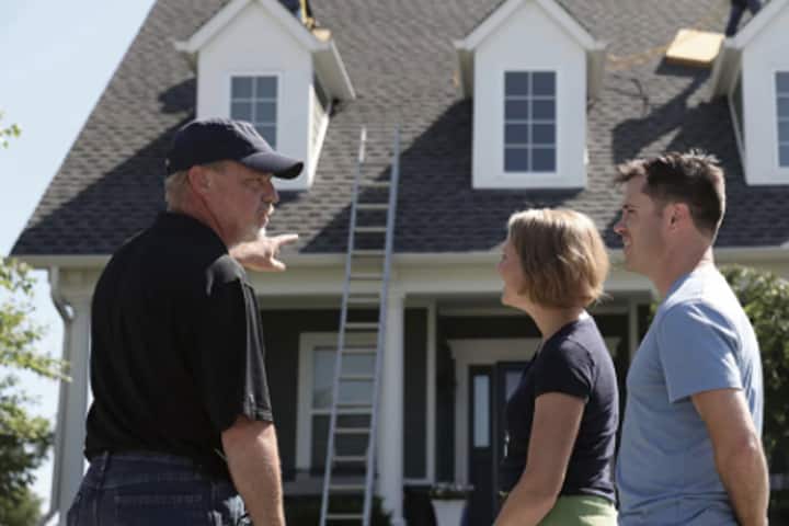 contractor talking to homeowners outside of their home while construction is in process